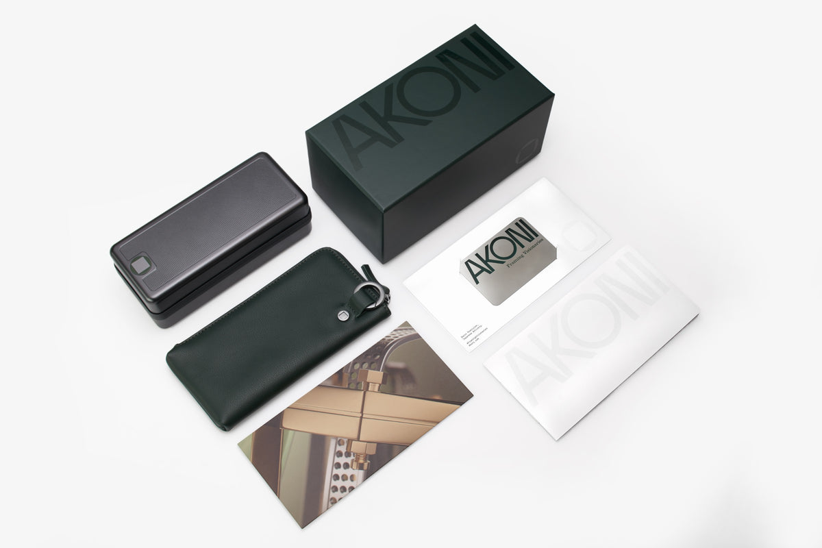 Confezione completa AKONI: scatola, custodia rigida in metallo, custodia morbida in pelle, panno e card